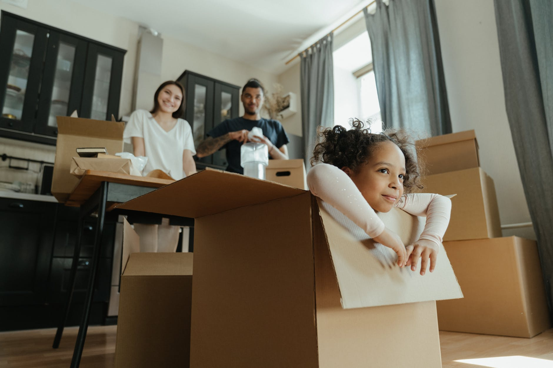 Happy family with young child unpacking boxes in their new home